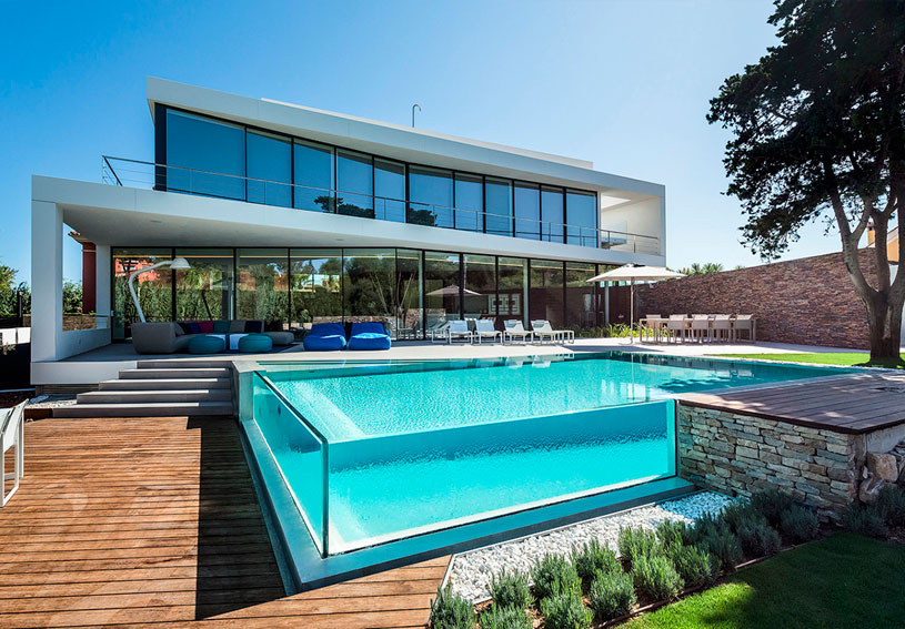 La moderna arquitectura con cristal, fachada de cristal solarizado que no deja ver el interior, piscina con muros de cristal